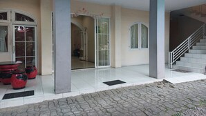A building entrance with a tiled floor, a staircase, and a door with glass panels. - R Residence (Medan)