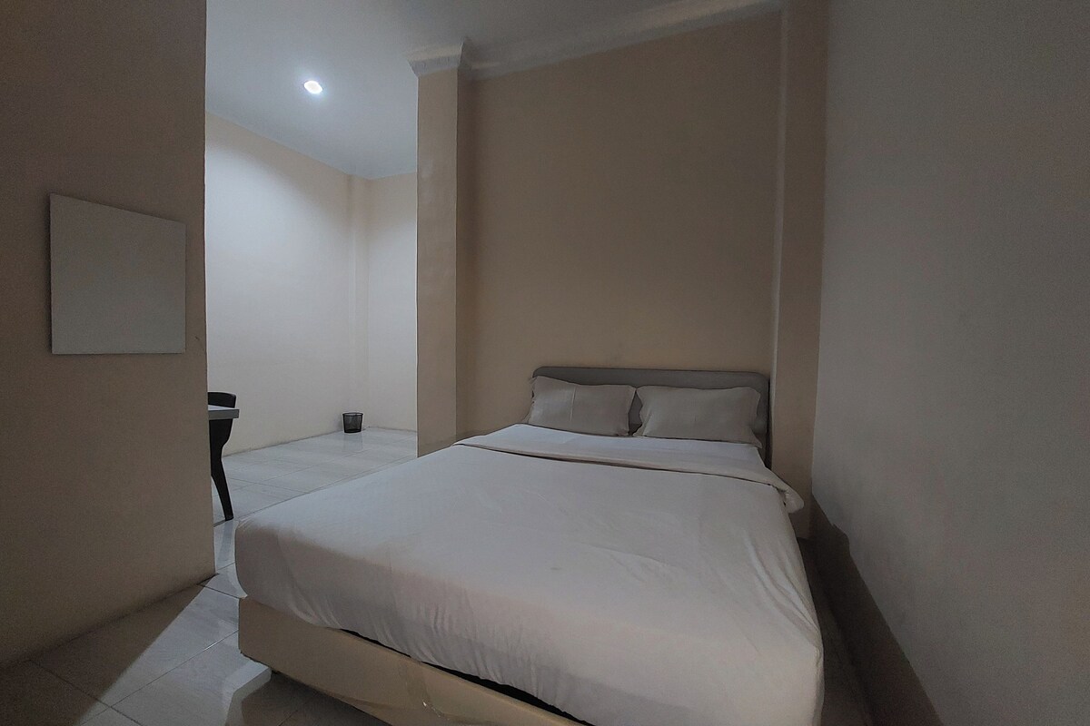 Une chambre à coucher avec un lit, une table de chevet et un luminaire fixé au mur.