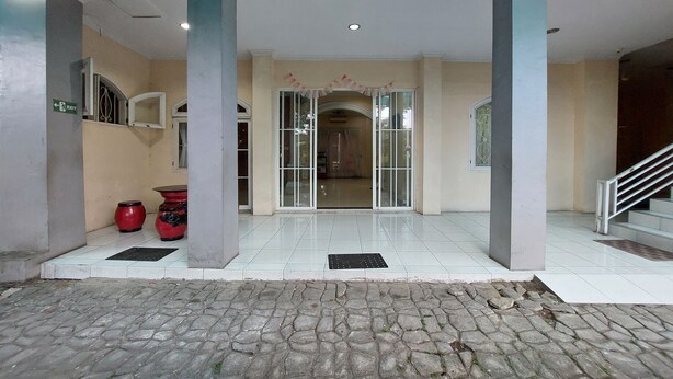 A building entrance with tiled flooring, a stone-paved area, and a staircase. - R Residence (Medan)
