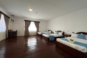 A hotel room with two beds, a dining table, and a window with curtains. - Nscc Casa De Vigan (Vigan)
