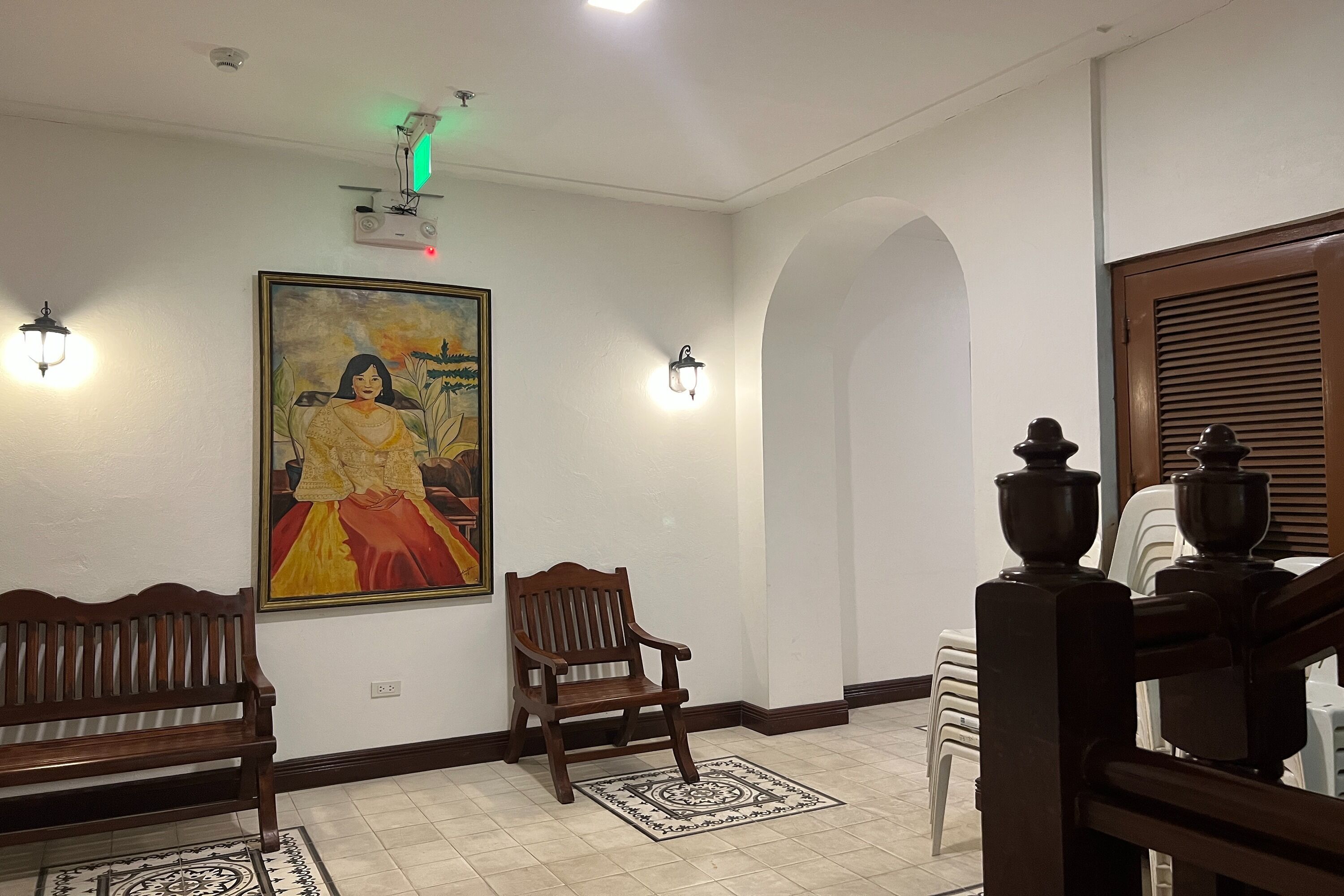 A hallway with a wooden bench, a chair, a painting, and a patterned rug.