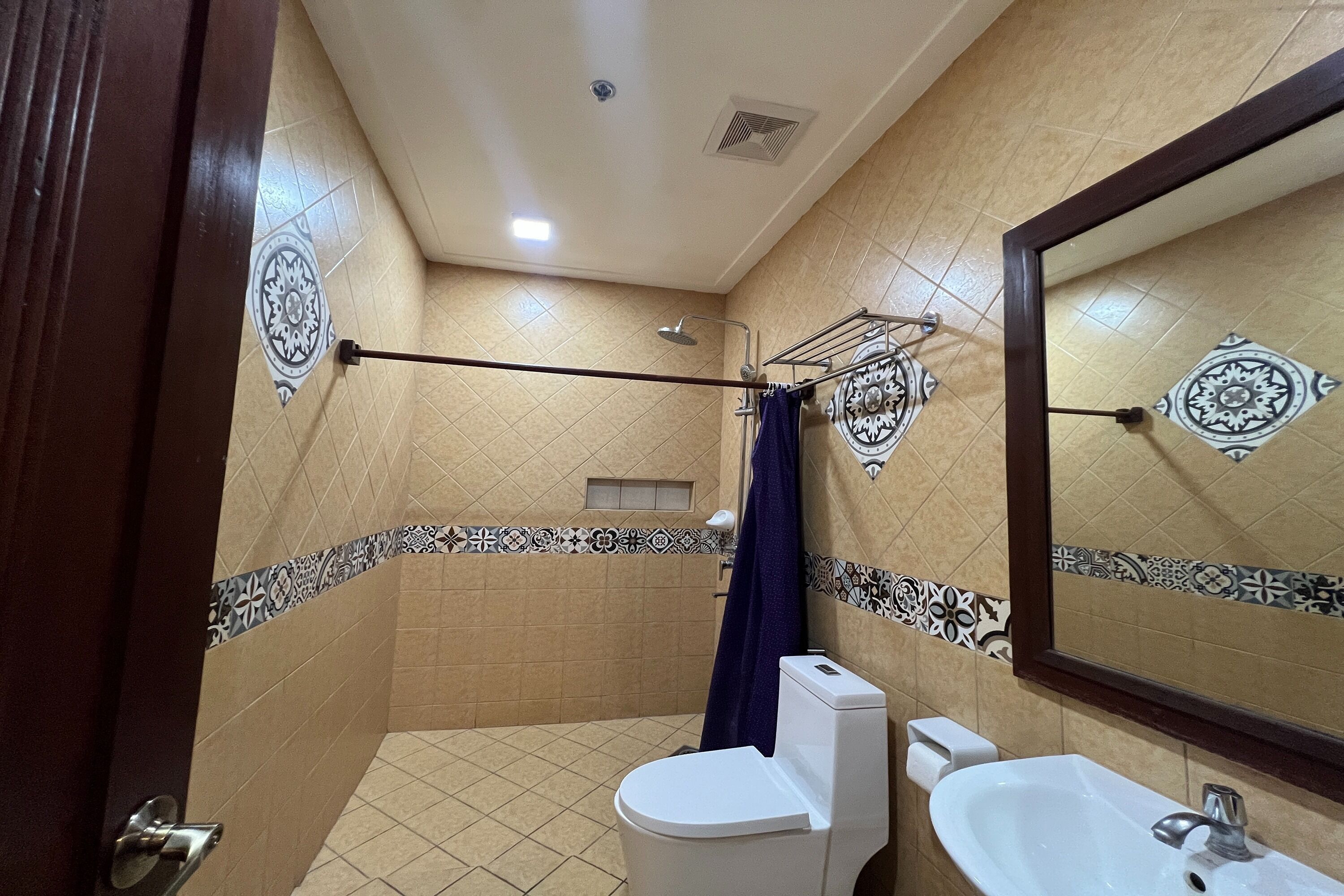 Un baño con inodoro, lavamanos, ducha y espejo.