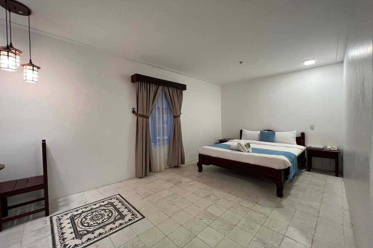 A bedroom with a bed, bedside table, and a chair.