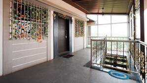 Um corredor espaçoso com design moderno, apresentando uma escadaria com grades ornamentadas e vista para o verde lá fora.