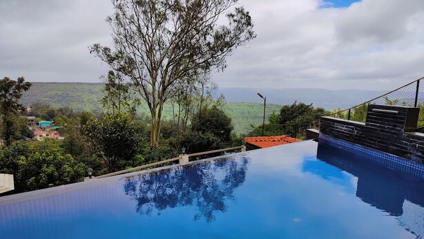 Uma piscina infinita com vista desobstruída da paisagem ao redor, incluindo árvores e colinas distantes.