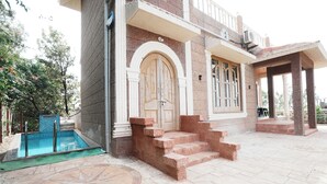 A building with a pool, steps leading to a door, and a covered area with columns. - Clifton Villa (Mahabaleshwar)