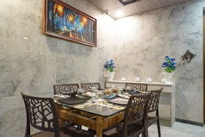 Un comedor con pared de mármol, un cuadro y jarrones decorativos.
