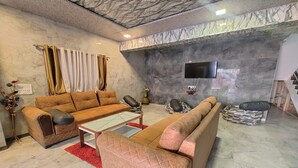 Una sala de estar con un juego de sofá, una mesa de centro y un televisor montado en la pared.