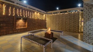 Un patio al aire libre con una chimenea, suelo de ajedrez e iluminación decorativa.