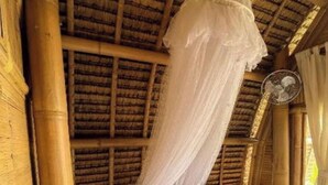 A room with a bed, a mosquito net, and a fan. - Tiny ECO Bamboo Ubud (Sebatu)