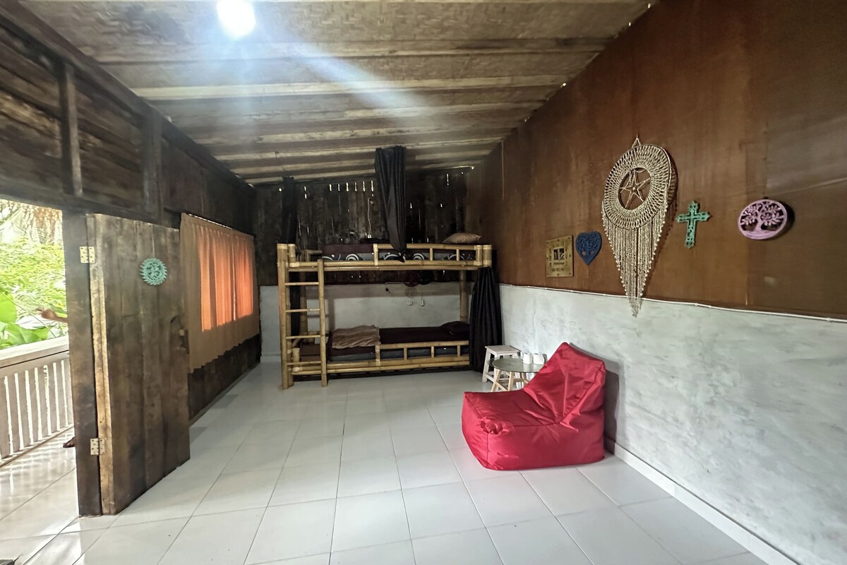 A room with a bunk bed, a red bean bag, a small table, and decorative wall art.