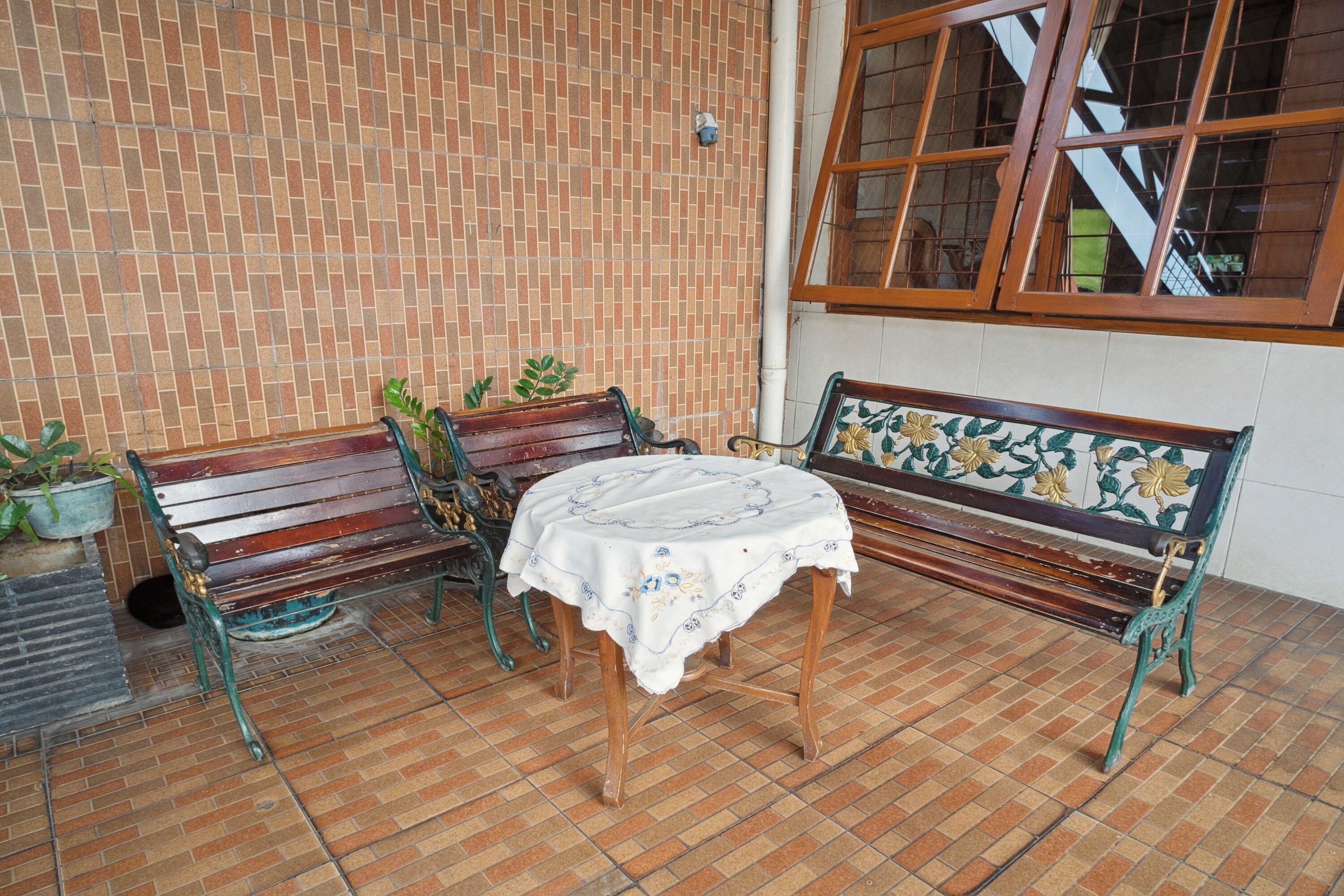 A patio with two wooden benches and a table covered with a white tablecloth.