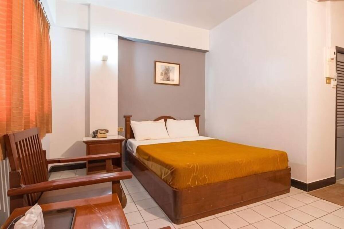 Une chambre à coucher avec un lit, une table de chevet, une chaise et un tableau au mur.