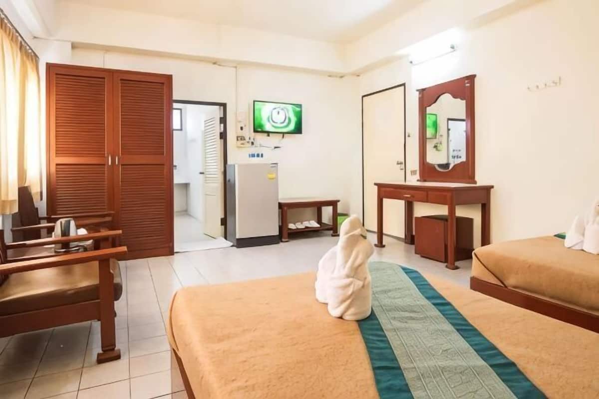 Une chambre d’hôtel équipée d’un lit, d’un bureau, d’une chaise, d’une armoire, d’une télévision et d’un miroir.