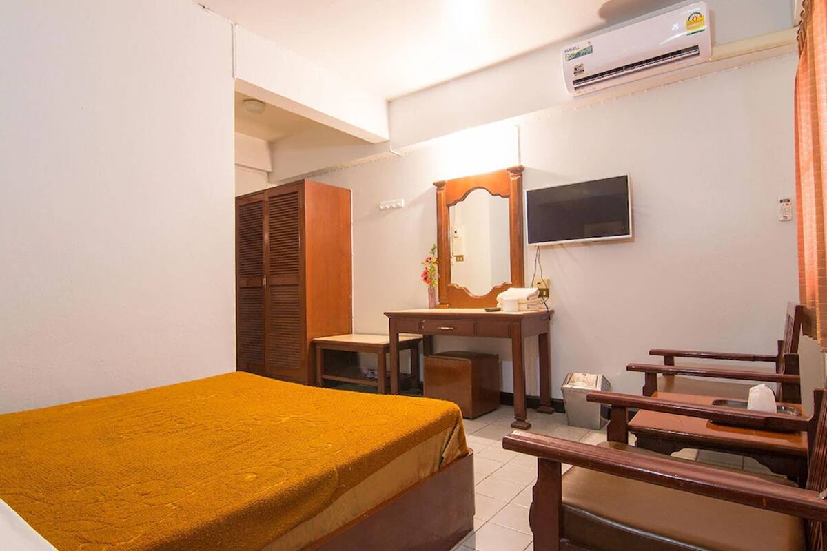 Une chambre d’hôtel équipée d’un lit, d’un bureau, d’une chaise, d’une télévision et d’un appareil de climatisation.