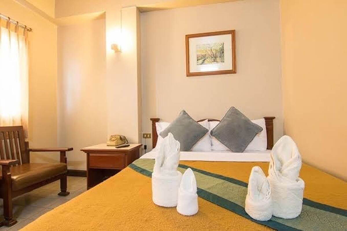 Une chambre d’hôtel avec un lit, des oreillers, une table de chevet, une chaise et des serviettes sur le lit.