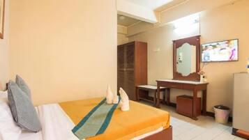 A hotel room with a bed, a desk, a mirror, a television, and a wardrobe.