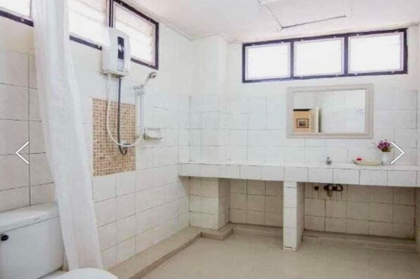 A bathroom with a toilet, a shower, a sink, and a mirror. - Khelang Nakorn Hotel (Lampang)