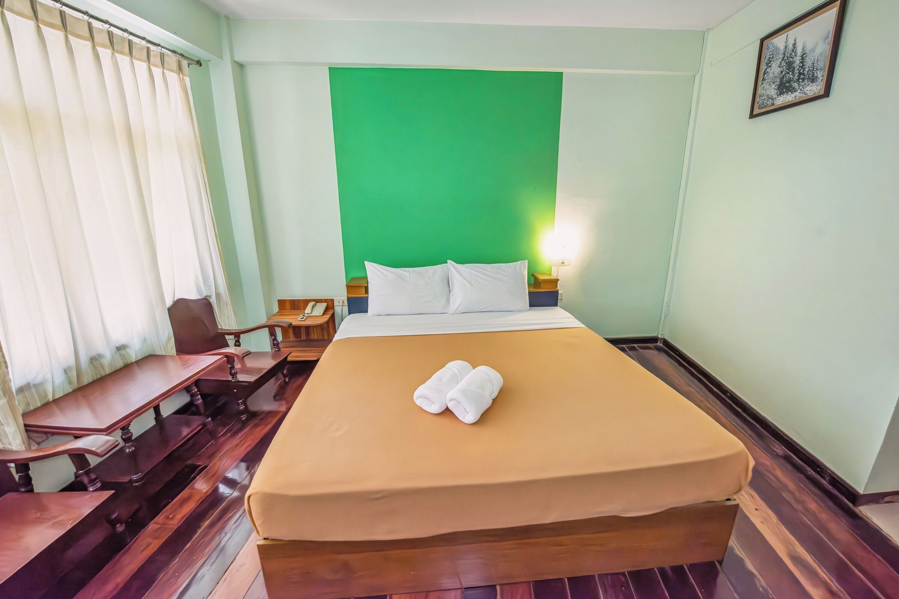 A hotel room with a bed, a desk, and a chair.