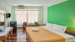 A hotel room with a bed, a desk, a chair, a television, and a window with curtains. - The Prince Hotel (Phitsanulok)
