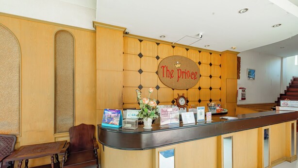 A reception desk with a sign reading "The Prince," a clock, and a vase with flowers. - The Prince Hotel (Phitsanulok)