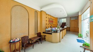 A hotel reception area with a wooden reception desk, a waiting area with chairs, and a wall-mounted sign that reads "The Prince." - The Prince Hotel (Phitsanulok)