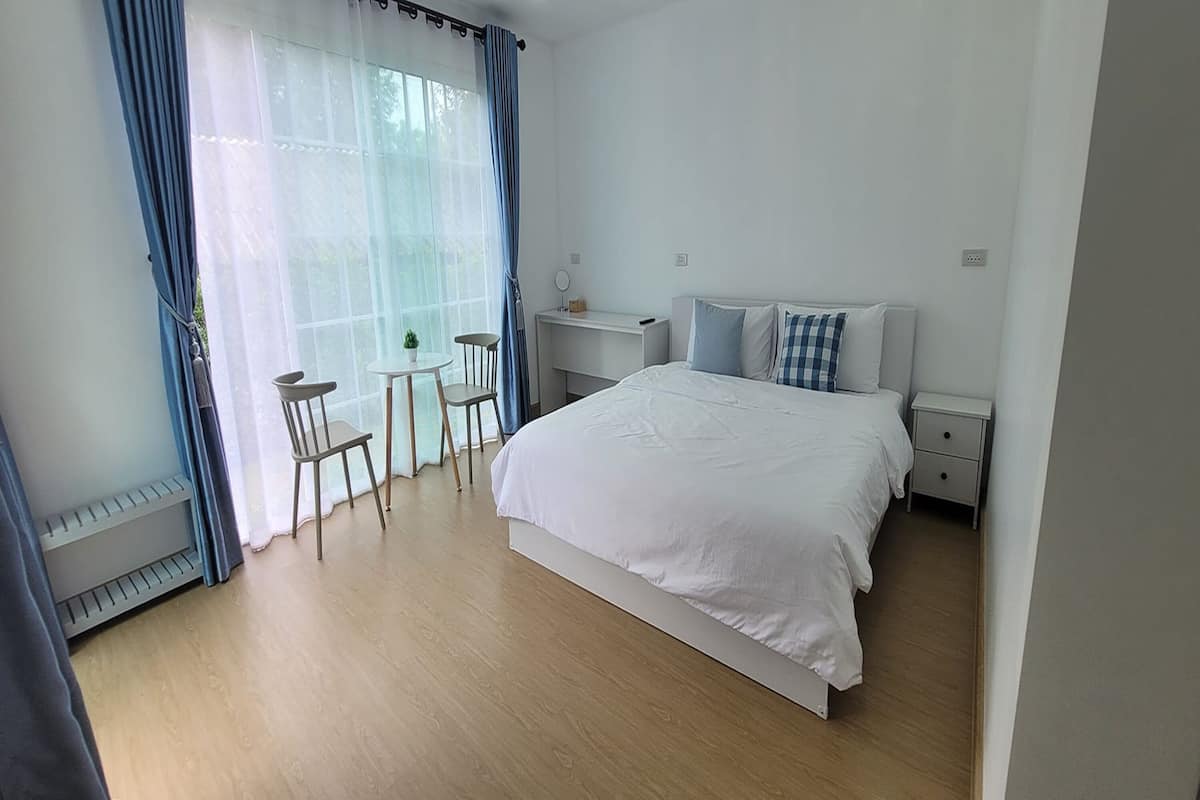 A bedroom with a bed, bedside table, and a desk with a chair.