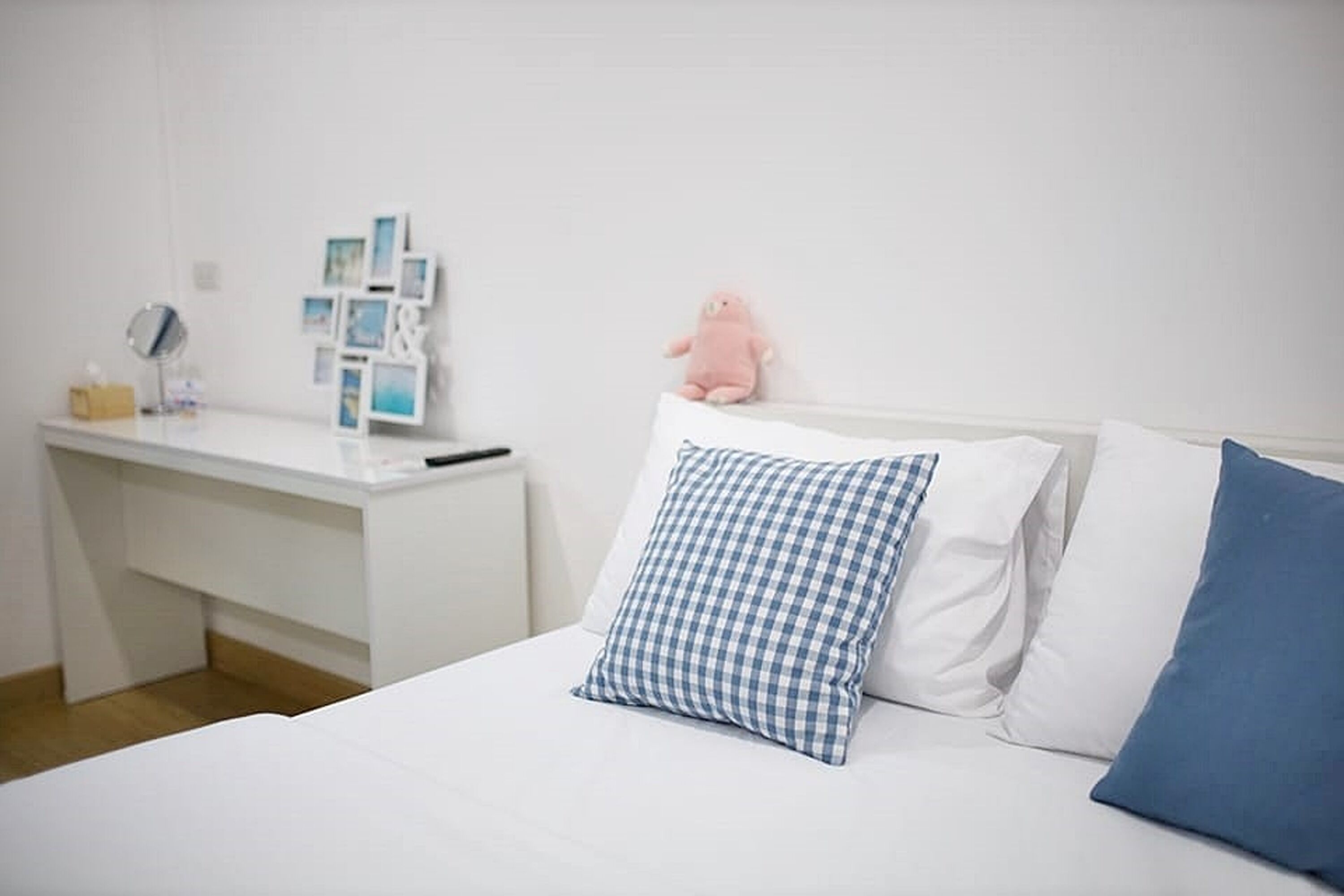 A neatly arranged bedroom with a bed, a bedside table, and a wall-mounted shelf.