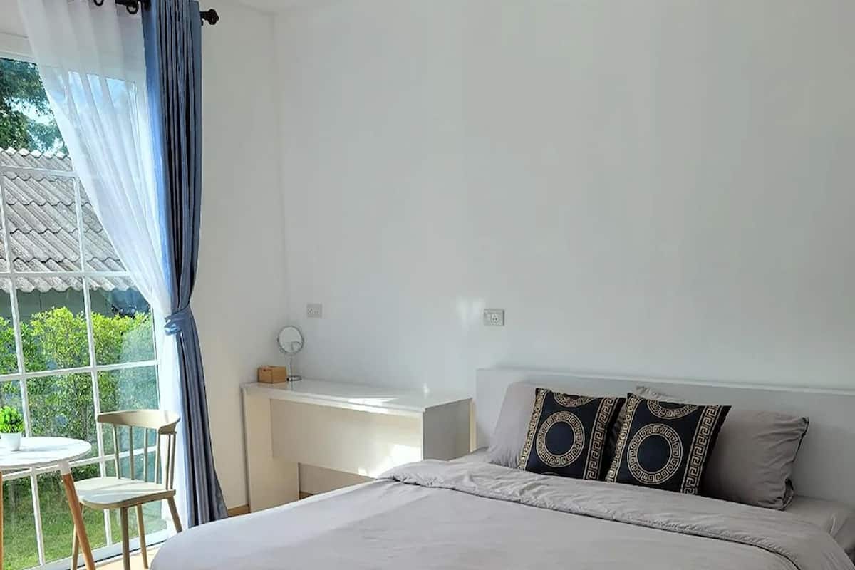 A modern bedroom with a large bed, a desk, and a chair.
