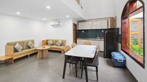 A modern kitchen with white cabinets, a black refrigerator, and a window with a view of greenery. - Mai Hotel (Ho Chi Minh City)