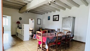 Un coin repas avec une table dressée pour six personnes, des chaises en bois, un buffet blanc et un sol carrelé.