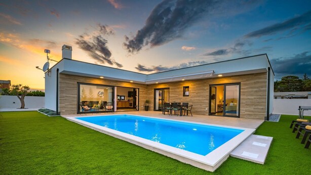 Een modern huis met een zwembad, grote glazen deuren en een verzorgd gazon.