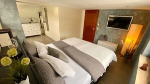 Un dormitorio moderno con una cama grande, mesitas de noche, un televisor y un espejo.