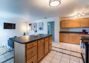 A modern kitchen with wooden cabinets, a black countertop, and a tiled floor. - 505 Fillmore Uint 12 | 1BR/1BA (Cape Canaveral)