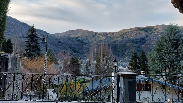 A balcony with wrought iron railing overlooking a mountainous landscape with houses and trees. - Très Spacieux T4 Dans un Chalet Traditionnel Entièrement Rénové, en Coeur de Village (Saint Lary Soulan)