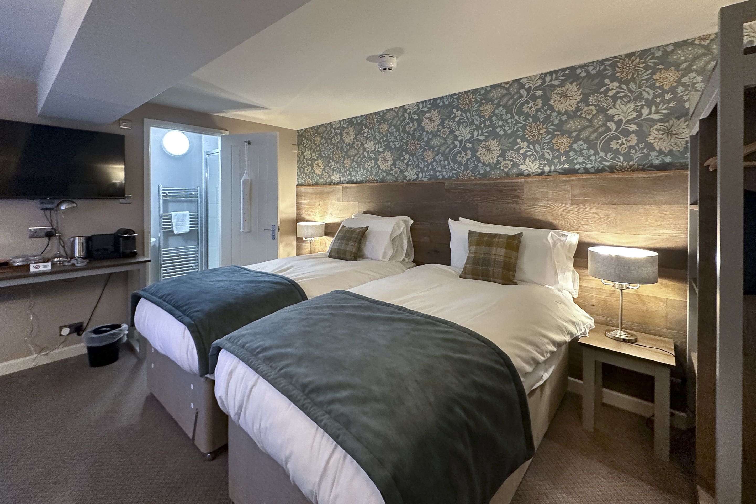 A hotel room with two beds, a TV, a desk, and a bathroom.