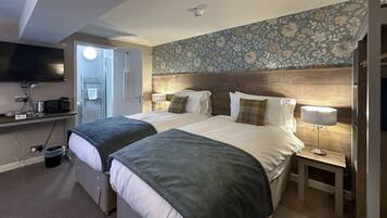 A hotel room with two beds, a TV, a desk, and a bathroom.