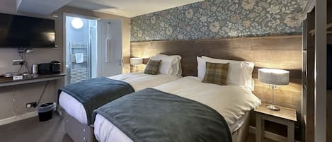 Une chambre d’hôtel avec deux lits, une télévision, un bureau et une salle de bain.