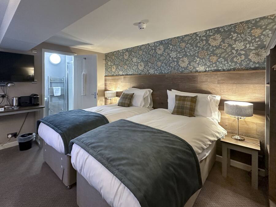 A hotel room with two beds, a TV, a desk, and a bathroom.