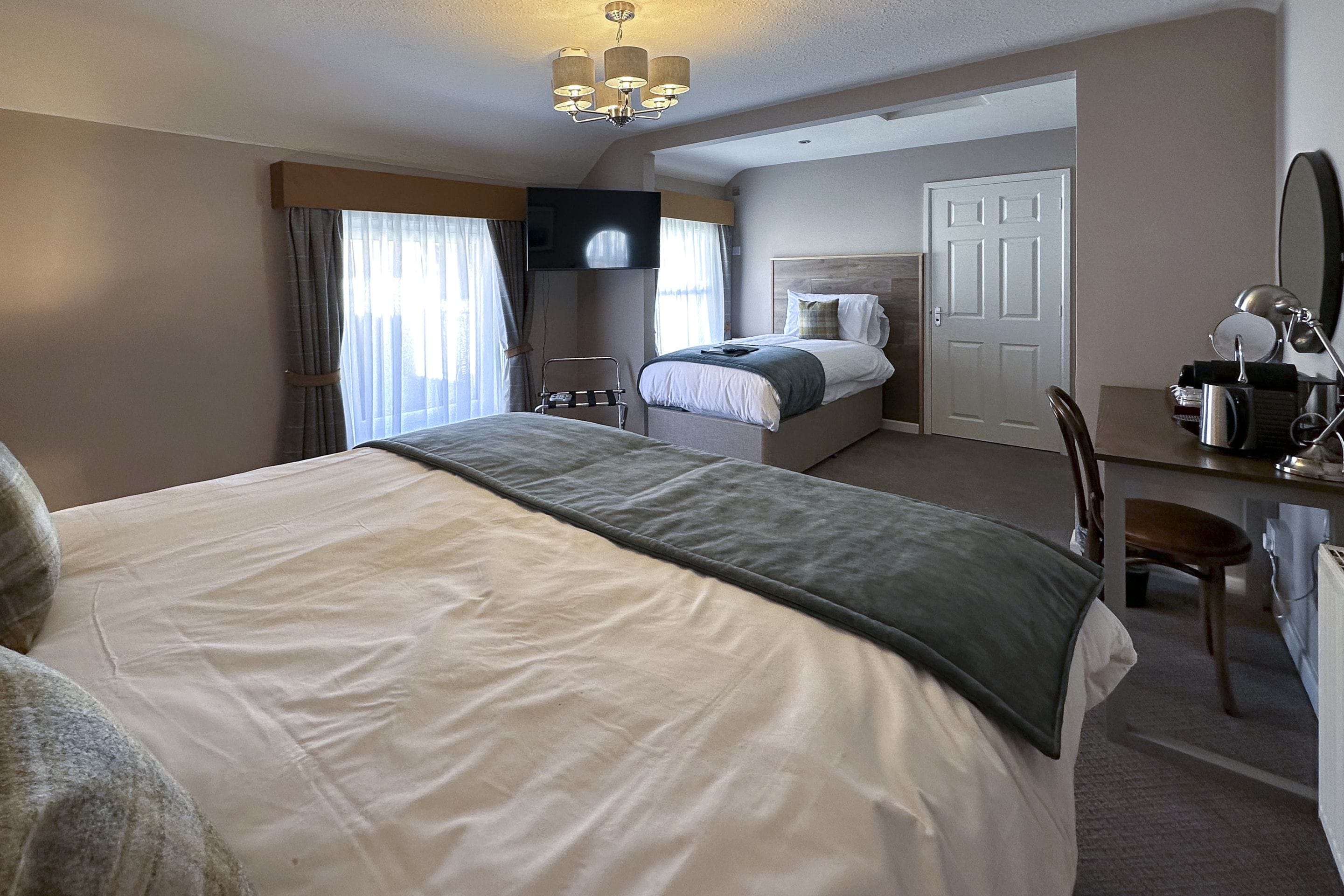 Una habitación de hotel con una cama grande, un escritorio con una silla, un televisor y una puerta.