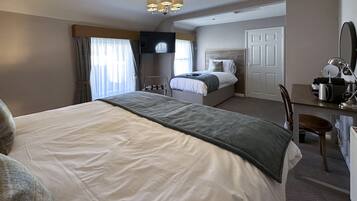 Una habitación de hotel con una cama grande, un escritorio con una silla, un televisor y una puerta.