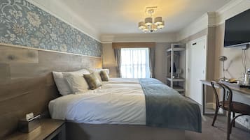 Een hotelkamer met een tweepersoonsbed, een bureau, een stoel, een televisie en een kledingkast.