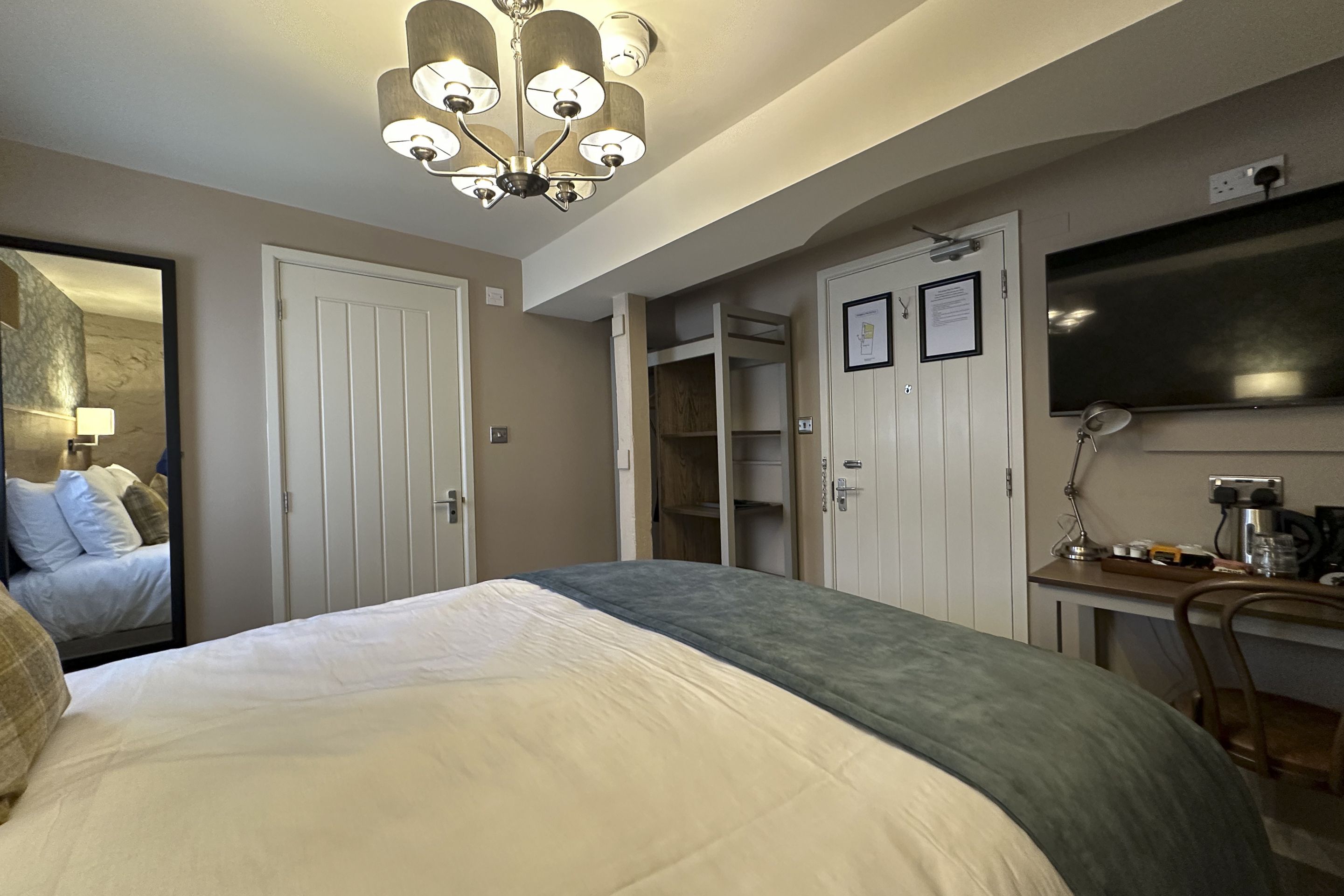 A hotel room with a bed, a desk, a chair, a television, and a wardrobe.