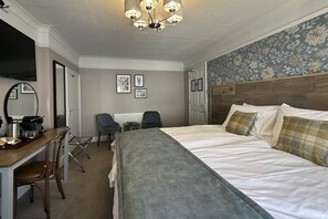 A hotel room with a bed, a desk with a chair, a television, and a mirror.