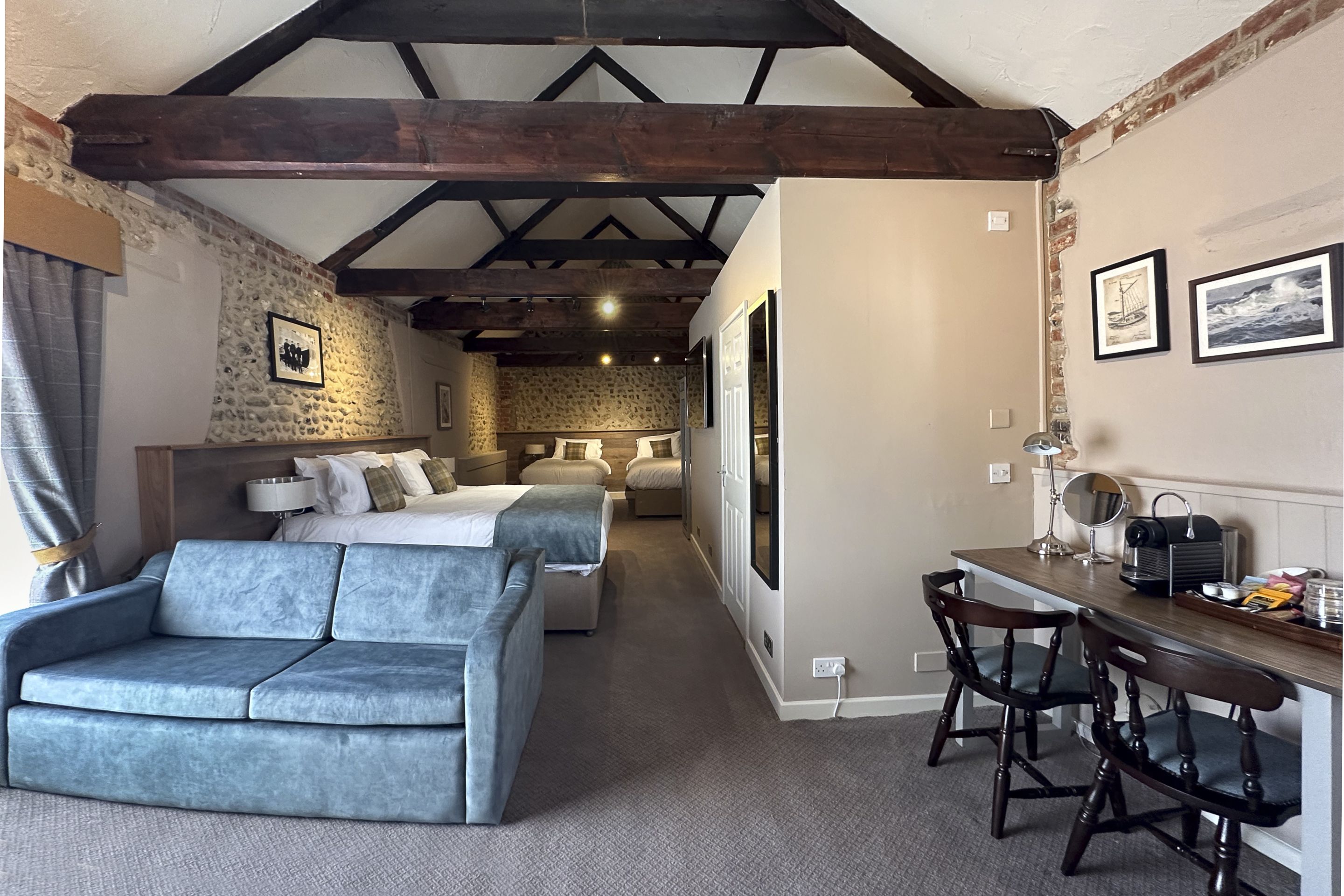 A cozy room with a sofa, a bed, and a desk area with chairs.