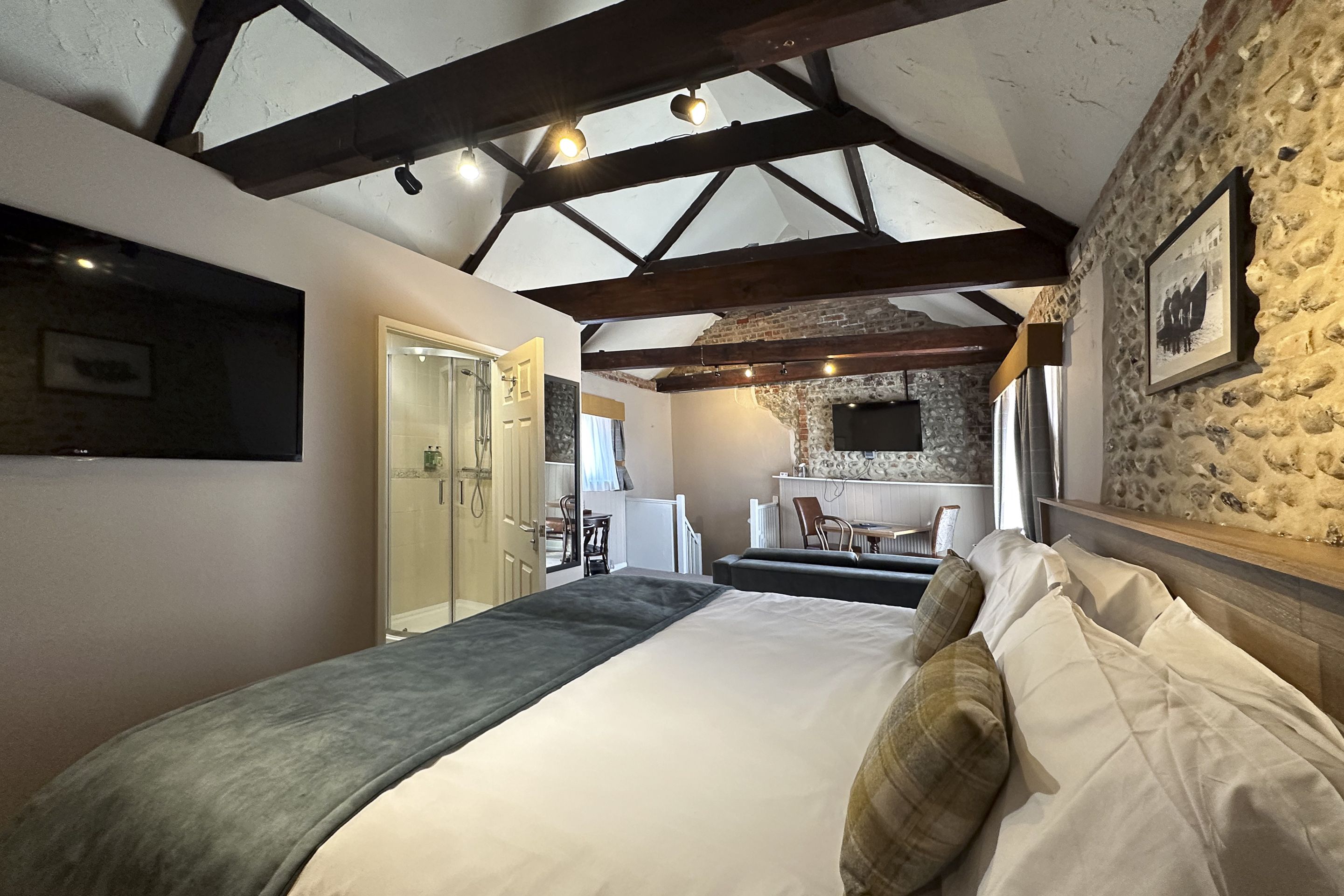 A bedroom with a bed, a desk, and a stone wall.