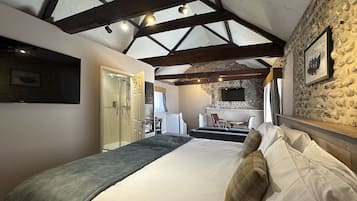 A bedroom with a bed, a desk, and a stone wall.