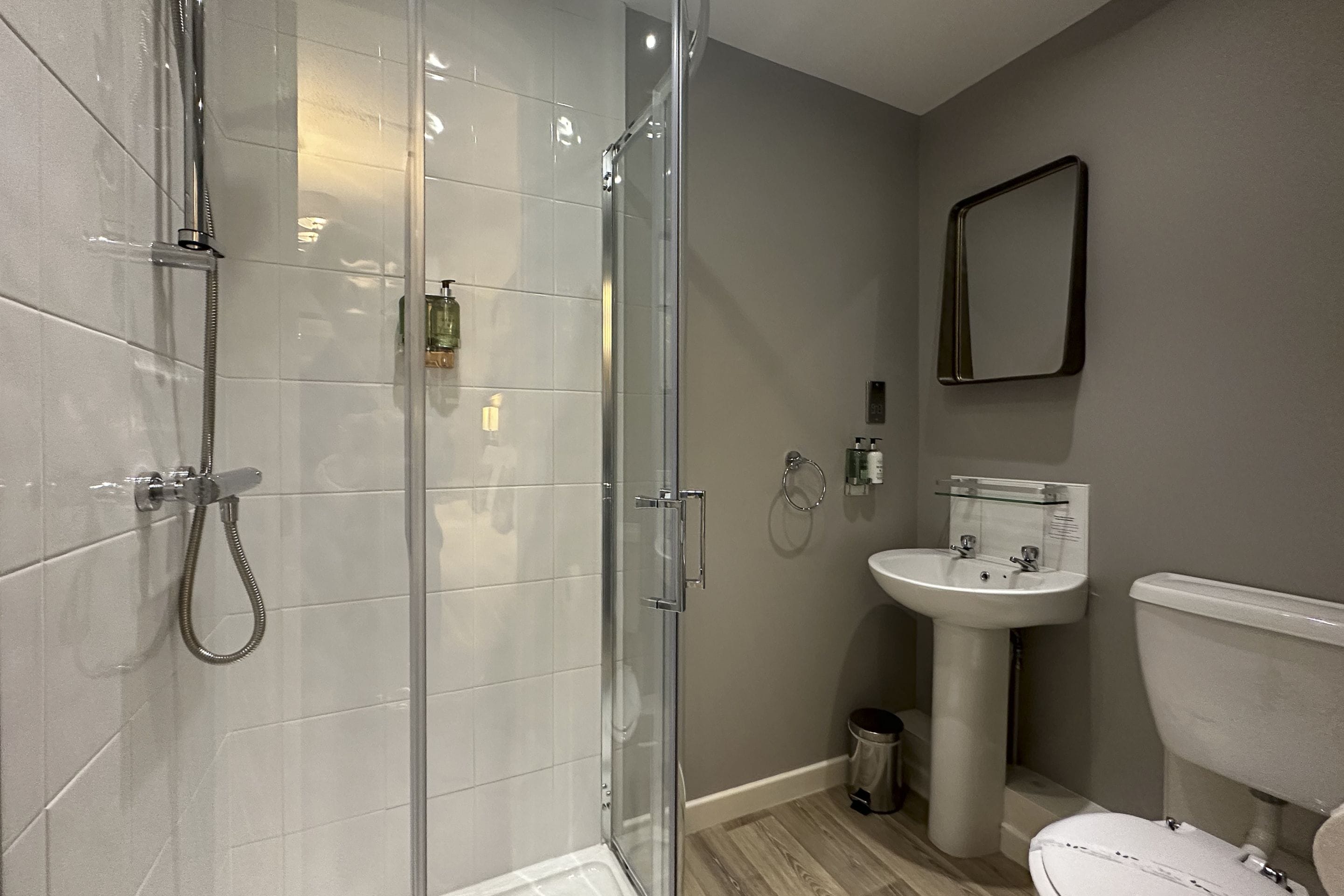 Een moderne badkamer met een douchecabine van glas, een wit wastafelmeubel en een toilet.