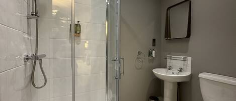 Een moderne badkamer met een douchecabine van glas, een wit wastafelmeubel en een toilet.