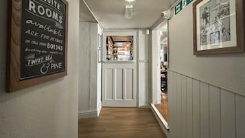 Un pasillo con un letrero que indica disponibilidad de suites, un área de bar visible a través de una puerta y un cuadro en la pared.
